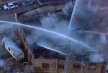 Firefighters using ladder trucks to battle the Joliet building fire at Union Signs.