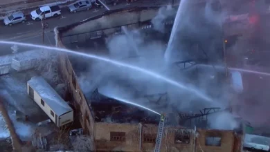 Firefighters using ladder trucks to battle the Joliet building fire at Union Signs.