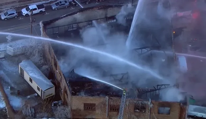 Firefighters using ladder trucks to battle the Joliet building fire at Union Signs.
